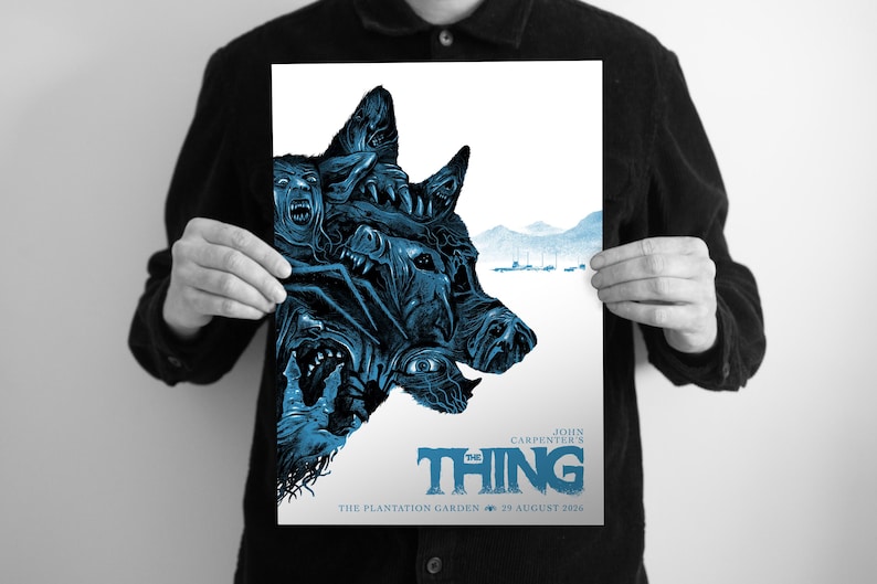 Puede incluir: Un p&oacute;ster rectangular con una ilustraci&oacute;n en azul y blanco de una criatura de m&uacute;ltiples caras. El texto dice John Carpenter's The Thing, The Plantation Garden, 25 August 2026. La obra representa una cabeza canina grande y distorsionada con ojos.