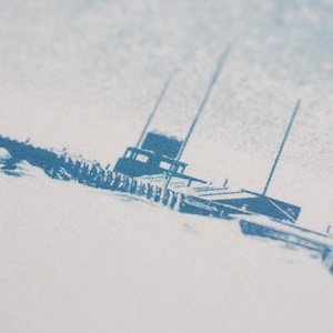 Puede incluir: Una impresi&oacute;n de tinta azul sobre una superficie de papel blanco texturizado que presenta una ilustraci&oacute;n estilizada de un barco con cabina y m&aacute;stiles altos. La tinta muestra una textura granulada y desgastada con tonos de azul variados.