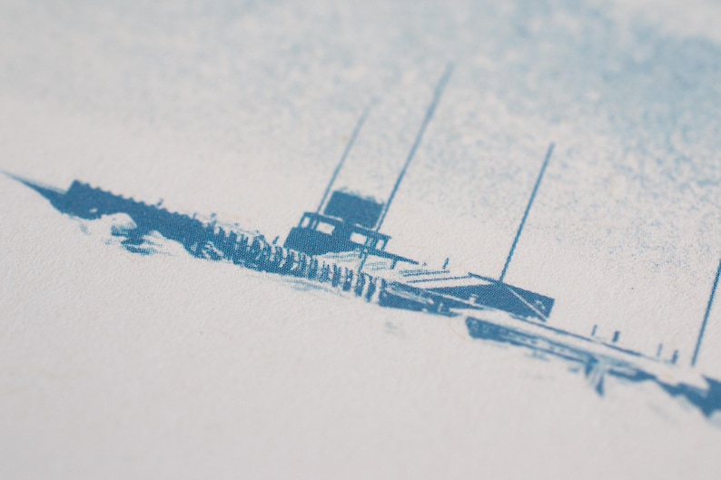 Puede incluir: Una impresi&oacute;n de tinta azul sobre una superficie de papel blanco texturizado que presenta una ilustraci&oacute;n estilizada de un barco con cabina y m&aacute;stiles altos. La tinta muestra una textura granulada y desgastada con tonos de azul variados.