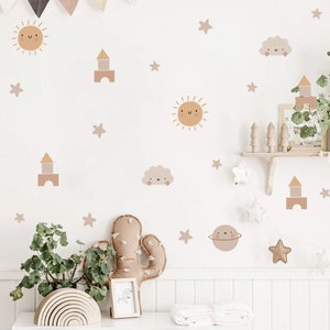 May include: A set of beige and brown wall decals featuring a sun, clouds, stars, and a block tower. The decals are on a white wall in a nursery or child's room.