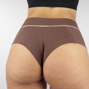 May include: Brown shorts with a white stitched waistband. The shorts are made of a textured fabric and have a simple, classic design. The shorts are a solid brown color.