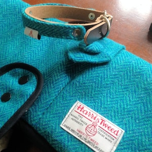 Op de afbeelding: Een tealblauwe tweed hondenriem met een bruin leren band en zilveren hardware. De riem heeft een label met de tekst "Harris Tweed" en "The Harris Tweed Authority Certification Trade Mark" met een geweven wapen. Handgeweven in de Buiten-Hebriden.
