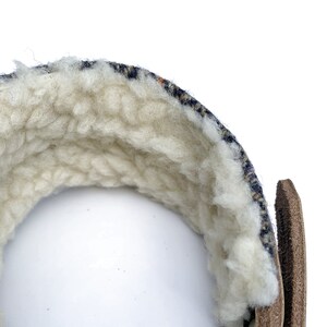 May include: A close-up of the inside of a blue and white patterned fabric wrist cuff. The cuff is lined with a soft, white fleece material.