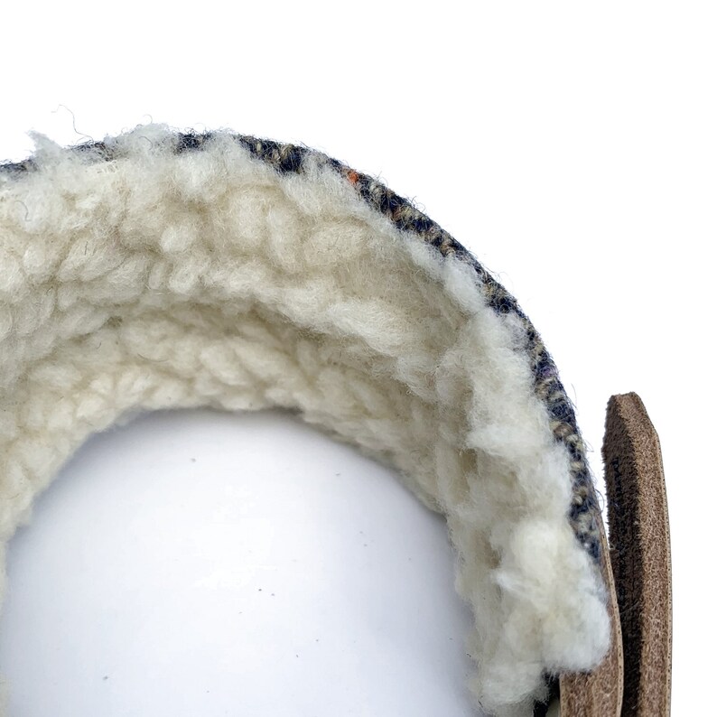 May include: A close-up of the inside of a blue and white patterned fabric wrist cuff. The cuff is lined with a soft, white fleece material.
