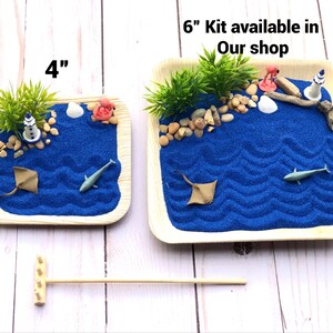 May include: Two blue sand tray kits with a beach theme. The smaller tray is 4 inches and the larger tray is 6 inches. Both trays have blue sand, a lighthouse, a seashell, a starfish, and a palm tree. The text "6" Kit available in Our shop" is printed on the image.