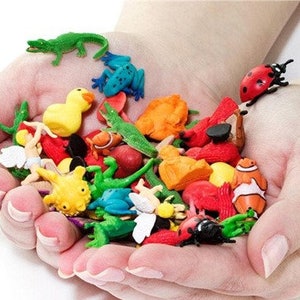 Pode incluir: Uma cole&ccedil;&atilde;o de figuras de animais de pl&aacute;stico coloridas, incluindo uma joaninha, um crocodilo, um sapo, um peixe, uma borboleta e alguns outros insetos. As figuras s&atilde;o todas pequenas e est&atilde;o sendo seguradas na m&atilde;o de uma pessoa.