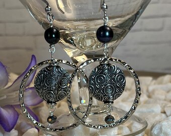 Antique silver earrings featuring a richly detailed coin inside a slim hammered silver circle dangling from black peacock fresh water pearl
