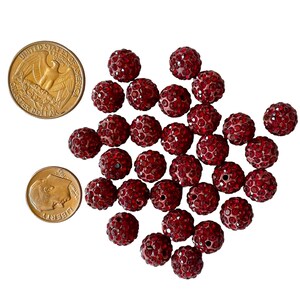 May include: A pile of red rhinestone beads. The beads are round and have a sparkly finish.