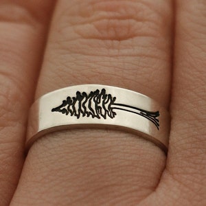 May include: A silver ring with a tree design engraved on the band.