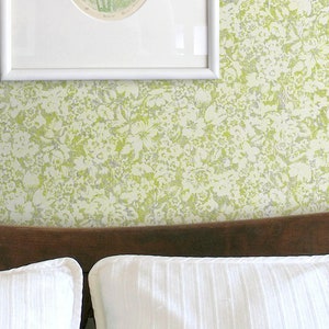 K&ouml;nnte beinhalten: Ein wei&szlig;es Bett mit einem braunen Kopfteil und zwei wei&szlig;en Kissen. Die Wand hinter dem Bett ist mit einer gr&uuml;n-wei&szlig;en Blumen-Tapete bedeckt.