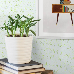 May include: A wooden desk with black metal legs, a laptop, a potted succulent, a stack of books, and a pair of glasses. The desk is in front of a white wall with a green speckled pattern.