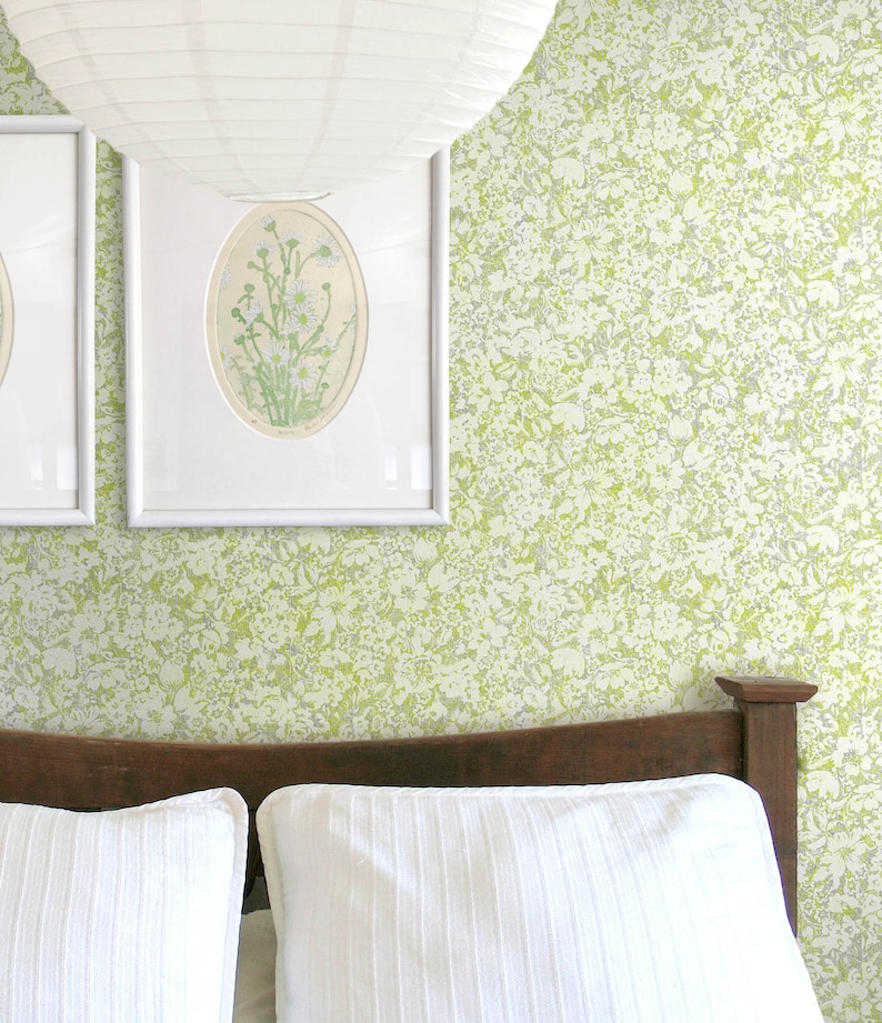 K&ouml;nnte beinhalten: Ein wei&szlig;es Bett mit einem Holz-Kopfteil und zwei wei&szlig;en Kissen. Die Wand hinter dem Bett ist mit einer gr&uuml;n-wei&szlig;en Blumen-Tapete bedeckt.