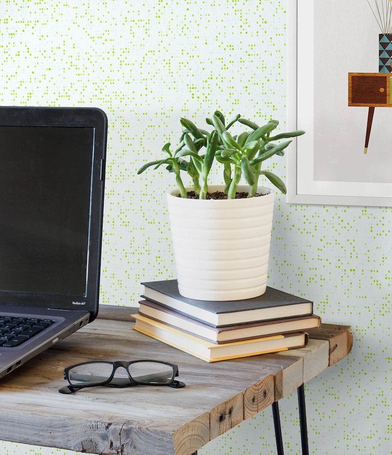 May include: A white ceramic planter with a succulent plant inside, sitting on a stack of books on a wooden table. The background is a light green and white patterned wallpaper.