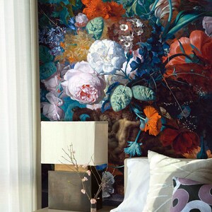 Op de afbeelding: Een slaapkamer met een wit bed, een witte lamp en een bloemenbehang met een boeket kleurrijke bloemen, waaronder rozen, tulpen en lelies.