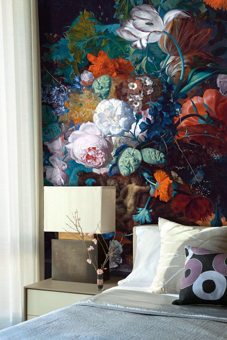 Op de afbeelding: Een slaapkamer met een wit bed, een witte lamp en een bloemenbehang met een boeket kleurrijke bloemen, waaronder rozen, tulpen en lelies.