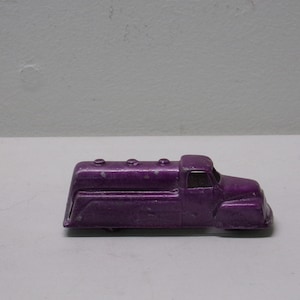 May include: A purple toy truck with a tank on the back. The truck has four wheels and a cab with a windshield.