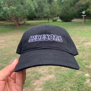 May include: A black baseball cap with white embroidered text that reads "BEBESOTA" in a retro font.