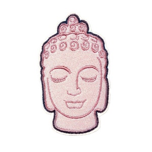 May include: Embroidered patch of a pink Buddha head with closed eyes and a serene expression. The Buddha is wearing a crown of small, circular designs.