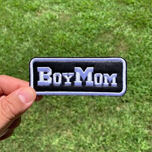 May include: Black and white embroidered patch with the text "Boy Mom" in white lettering.