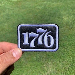 May include: A black leather patch with white stitching and the number "1776" in white embroidery.