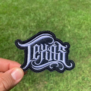 May include: A black and white embroidered patch with the word "DRIP" in a stylized font.