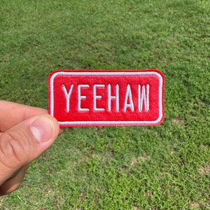May include: Red rectangular patch with white embroidered text that reads "YEEHAW".