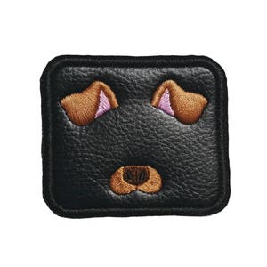 May include: Black leather patch with embroidered brown dog ears and nose.