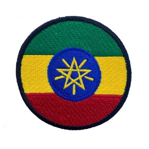 May include: A circular embroidered patch featuring the flag of Ethiopia. The flag is green, yellow, and red with a blue star in the center.