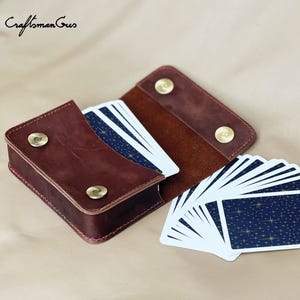May include: A dark brown leather card case with two brass snap closures, containing a deck of playing cards with a dark blue star pattern on the back. The text "CraftsmanGus" appears in the top left corner, and "PDF Pattern" is in the bottom right.