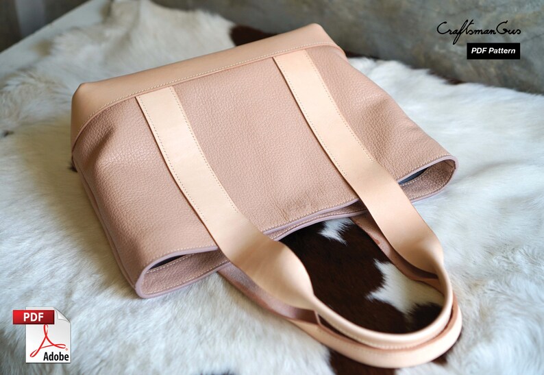 May include: A light pink leather tote bag with light tan straps. The bag has a textured surface and a rectangular shape. The bag is sitting on a white and brown fur-like surface. The text "Craftsman Gus PDF Pattern" is in the upper right corner.