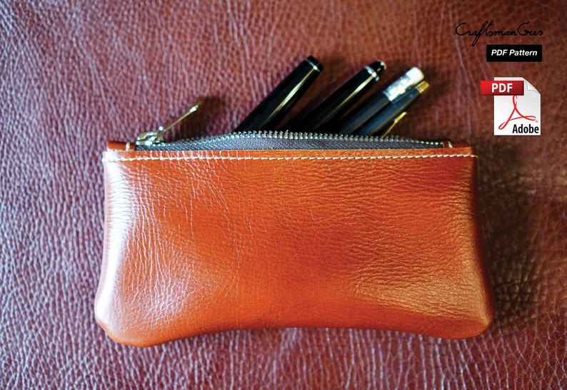 K&ouml;nnte beinhalten: Eine braune Leder-Rei&szlig;verschlusstasche mit wei&szlig;en N&auml;hten. Die Tasche ist mit Stiften und Bleistiften gef&uuml;llt.