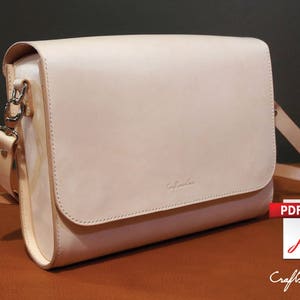 May include: A light beige leather messenger bag with a silver clasp and a long strap. The bag has a flap closure and a small logo on the front.