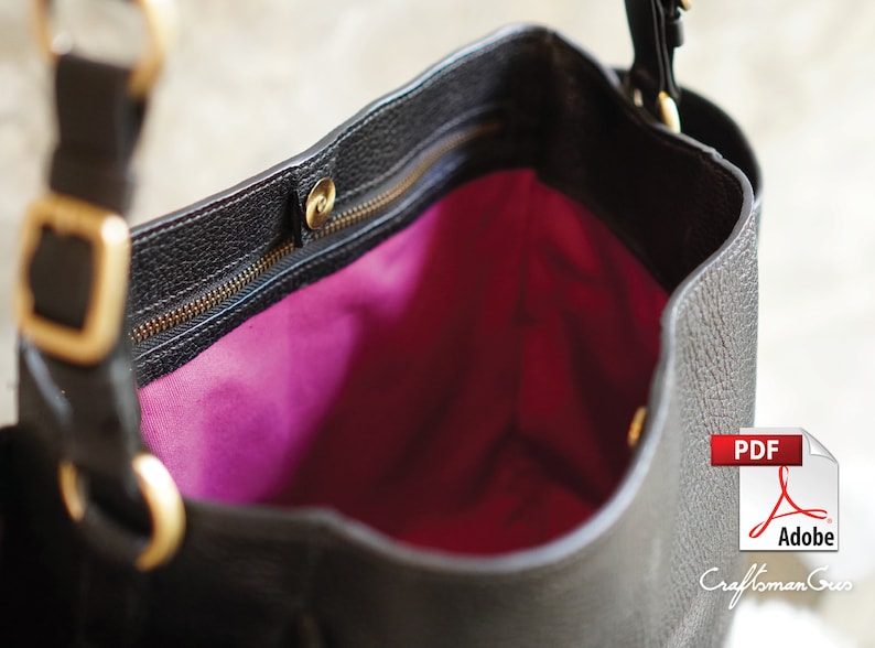 May include: A black leather tote bag with a gold zipper and hardware. The bag is open and the inside is lined with a bright pink fabric.