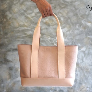 May include: A blush-colored leather tote bag with a rectangular shape and two long handles. The bag has a textured body and a smooth, lighter-colored base and straps. The text "Craftsman Gus PDF Pattern" is visible in the upper right corner.