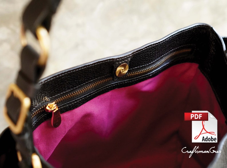 May include: The inside of a black leather handbag with a gold zipper and a pink lining. The zipper has a gold pull with a small decorative piece.