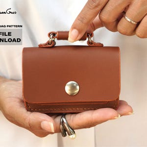 May include: A brown leather bag with a silver clasp and a silver button. The bag is being held in a person's hand. The text "PDF FILE DOWNLOAD" is visible in the image.