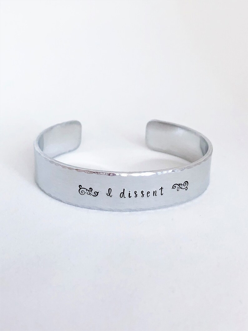 May include: A silver metal bracelet with the words "I dissent" engraved on it.