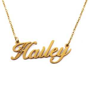 Puede incluir: Collar dorado con el nombre "Hailey" en fuente cursiva. La letra "H" tiene tres pequeñas gemas transparentes. La cadena es de estilo eslabón delicado, y el colgante está centrado.