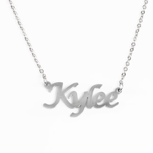 May include: A silver necklace featuring the name "Kylee" in a cursive script. The pendant hangs from a fine chain. The jewellery is set against a plain white backdrop.
