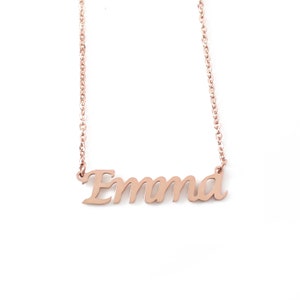 May include: A rose gold necklace with the name "Emma" in a cursive font. The pendant is suspended from a delicate chain, creating a personalized jewelry piece. The necklace is displayed against a white background.