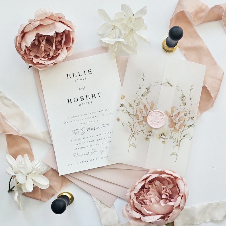Op de afbeelding: Huwelijksuitnodigingsset met een bloemenontwerp. De uitnodiging is wit met zwarte tekst en de RSVP-kaart is roze met zwarte tekst. De uitnodiging is versierd met een bloemenkrans en een roze waszegel.