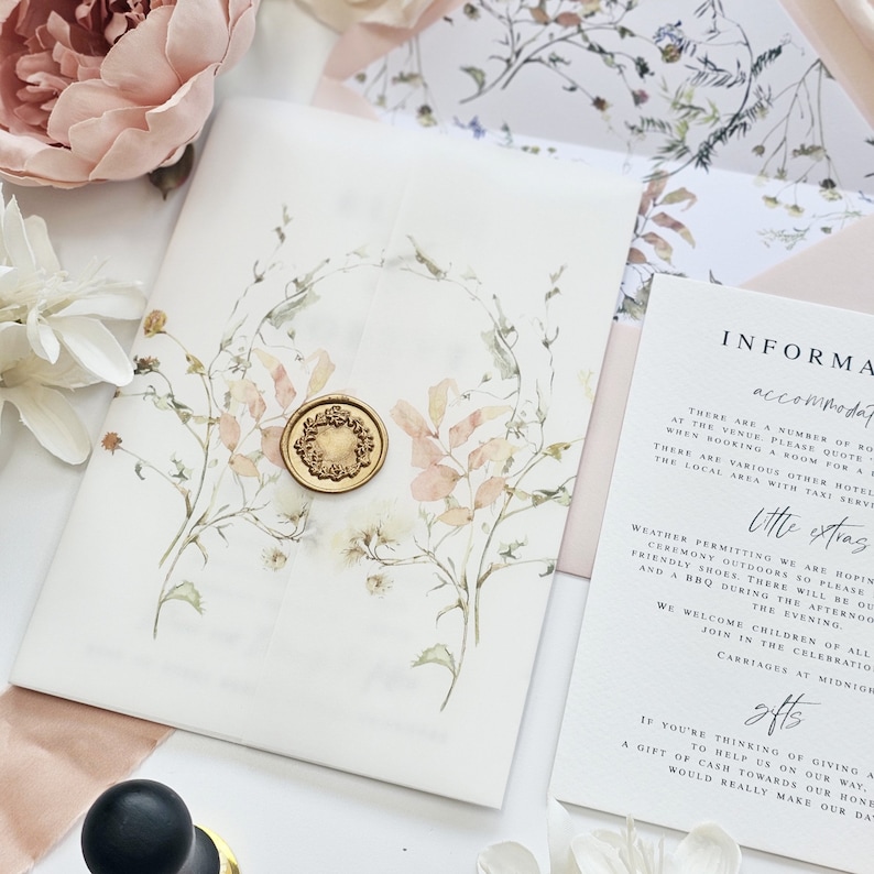 Op de afbeelding: Een witte huwelijksuitnodiging met een aquarelbloemendesign en een gouden waszegel. De uitnodiging bevat informatie over accommodatie, extra details en geschenken.