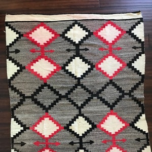 May include: A gray, black, white, and red Navajo rug with a geometric diamond pattern.