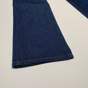 May include: A pair of dark blue denim jeans with a wide leg opening. The jeans are made of a soft, comfortable fabric and have a classic look.