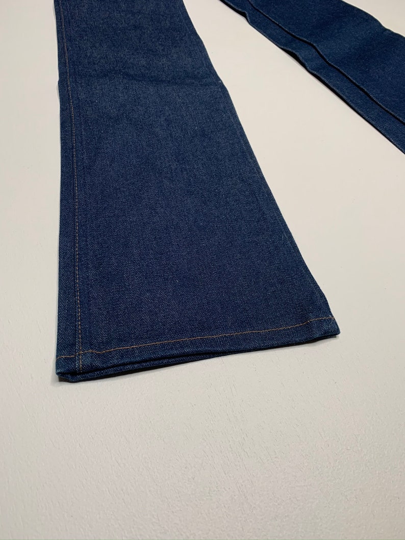 May include: A pair of dark blue denim jeans with a wide leg opening. The jeans are made of a soft, comfortable fabric and have a classic look.
