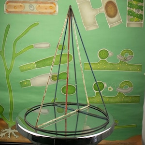 May include: A vintage metal pyramid-shaped display stand with a circular base and a mirrored surface. The stand is painted in white, red, and blue.