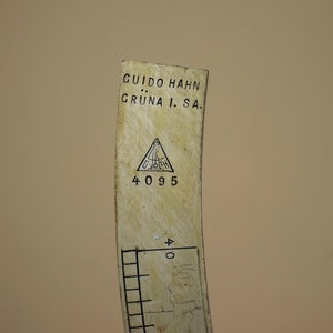 May include: Close-up of a white measuring tool with black markings. The tool is labeled "GUIDO HAHN GR&Uuml;NA I. SA." and has a triangular logo with the letters "G.H." inside. The number "4095" is printed below the logo.
