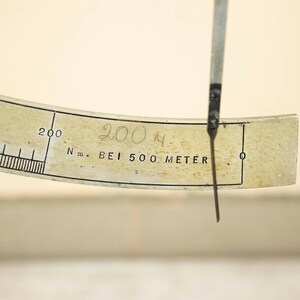 May include: A white measuring device with a black needle and a scale marked in meters. The needle is pointing to 200 meters. The device is labeled "N.m. BEI 500 METER".
