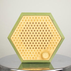 May include: A hexagonal shaped vintage radio with a green outer shell and a yellow speaker grill. The speaker grill has a pattern of small circles.