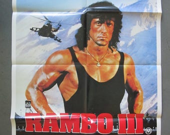May include: A movie poster for the film "Rambo III" starring Sylvester Stallone. The poster features a close-up of Stallone in a black tank top, with a helicopter flying in the background. The text "Rambo III" is in large red letters at the bottom of the poster.